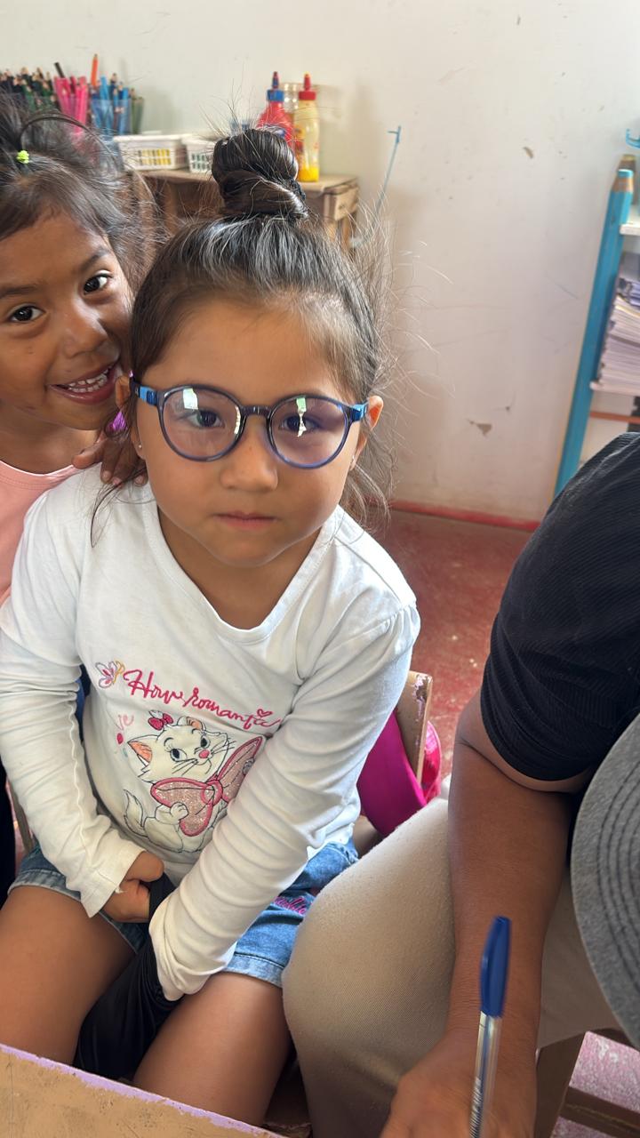Niña con lentes nuevos en el aula